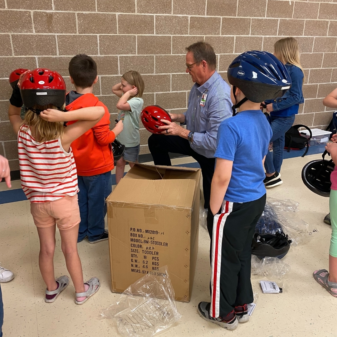 Mark Mattes, Chief Nursing Officer at Decatur County Hospital, fits helmets on students from the Lamoni Exploration Academy.