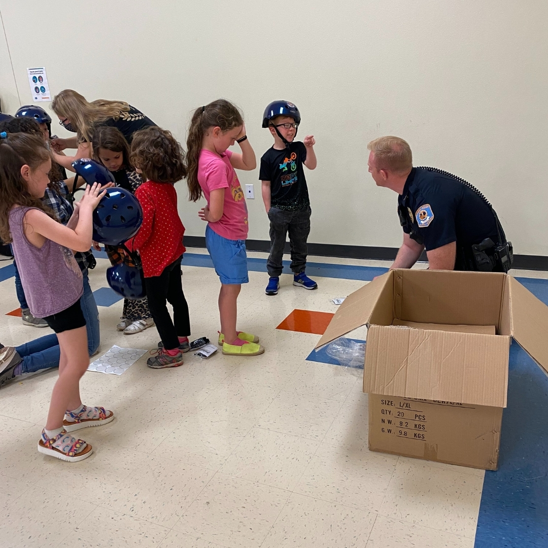 Lamoni Police Chief, Jon Barney, fits helmets on students from the Lamoni Exploration Academy.