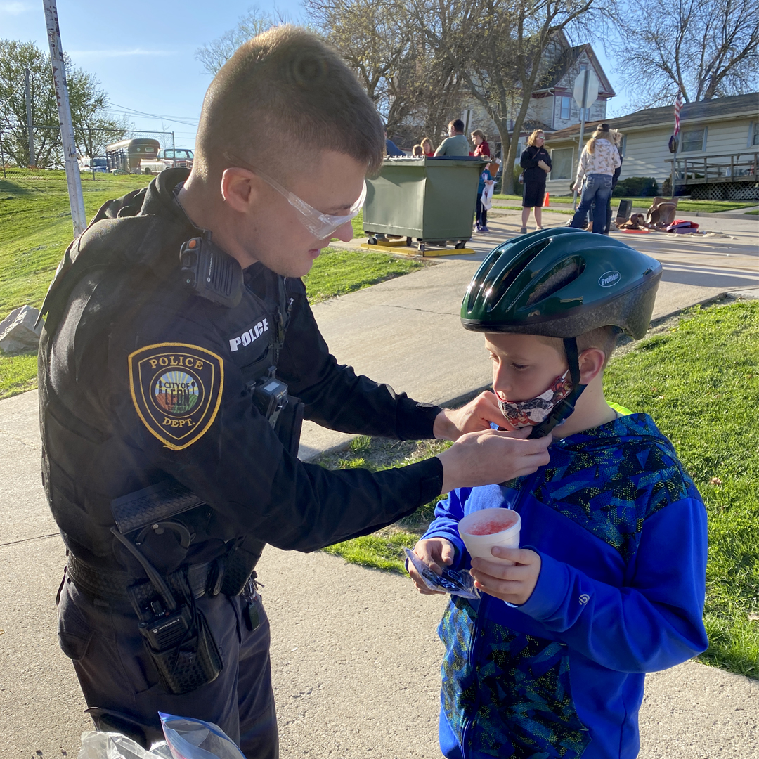 Leon Police Officer, Marcus Speakman, fits a helmet on Chris Schmidt at the Central Decatur School Spring Family Night.