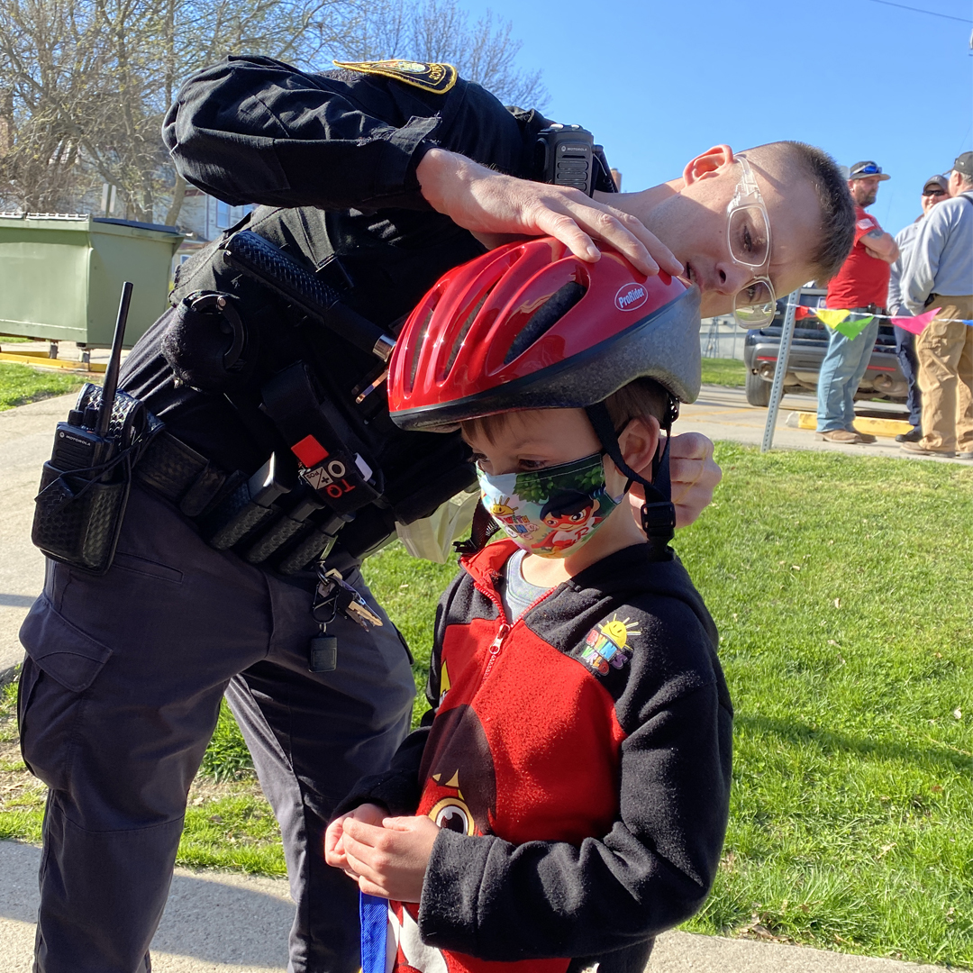 Leon Police Officer, Marcus Speakman, fits a helmet on Grey Greubel at the Central Decatur School Spring Family Night.