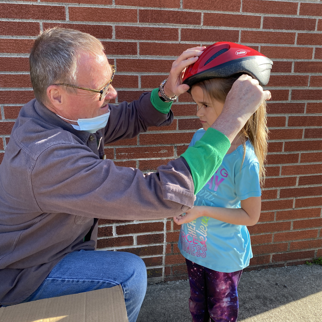 Mark Mattes, Chief Nursing Officer at Decatur County Hospital, fits a helmet on Kelsey Gingerich at the Central Decatur School Spring Family Night.