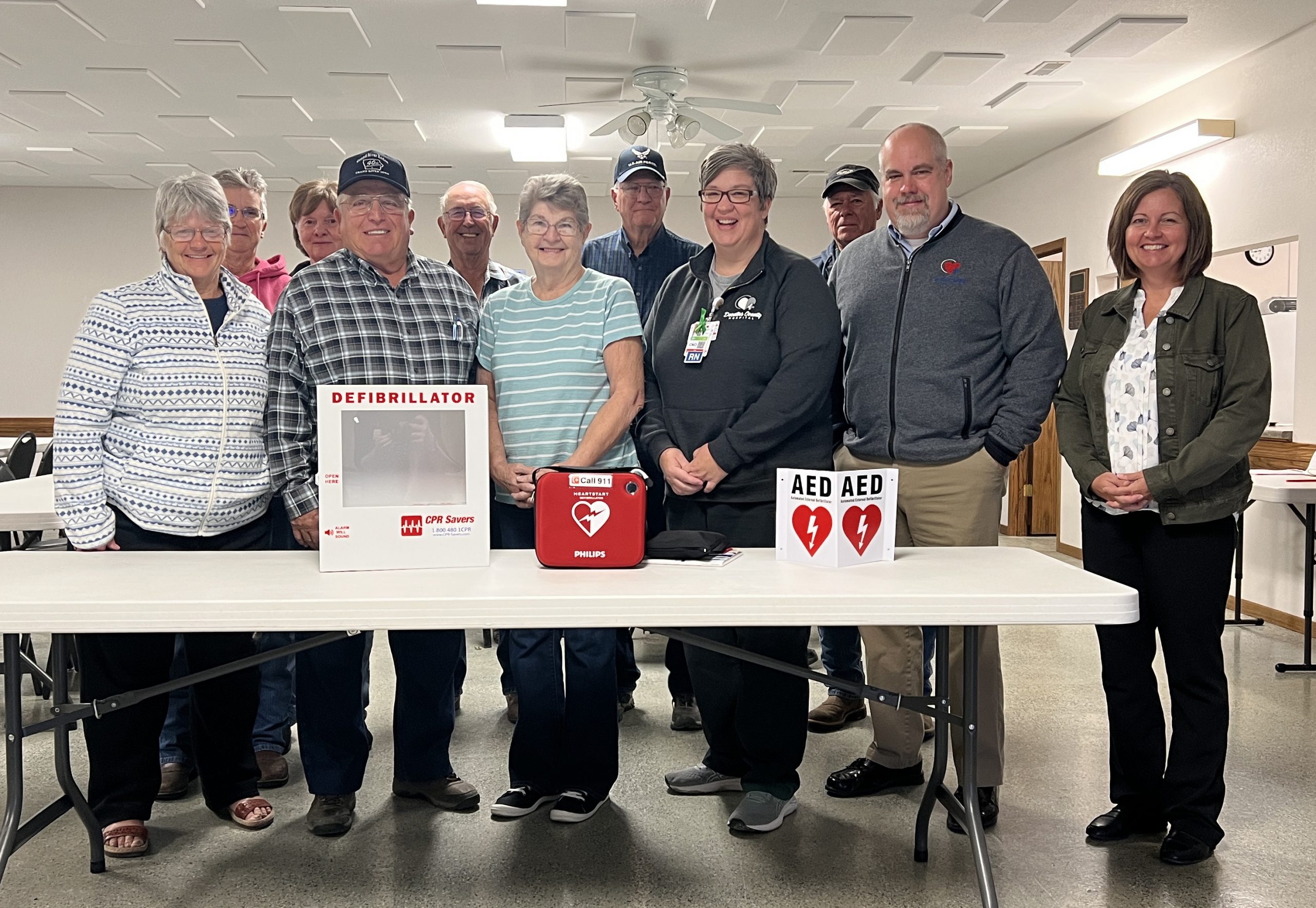 Decatur County Hospital Board Member Larry Griffin (second from left in the front row), along with staff members (starting fourth from the left in the front row) Kelly Barker, CNO; Mike Johnston, CEO; and Tara Spidle, CFO, present a defibrillator (AED) to the Grand River Community Center.